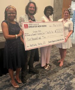 Three women and one man holding a large check for $10,000 presented by the Junior League of Greater New Bern.